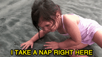 Video gif. A little girl in a swimsuit lies down on wet sand. Text, I take a nap right here. Video gif. A little girl in a swimsuit lies down on wet sand. Text, I take a nap right here.